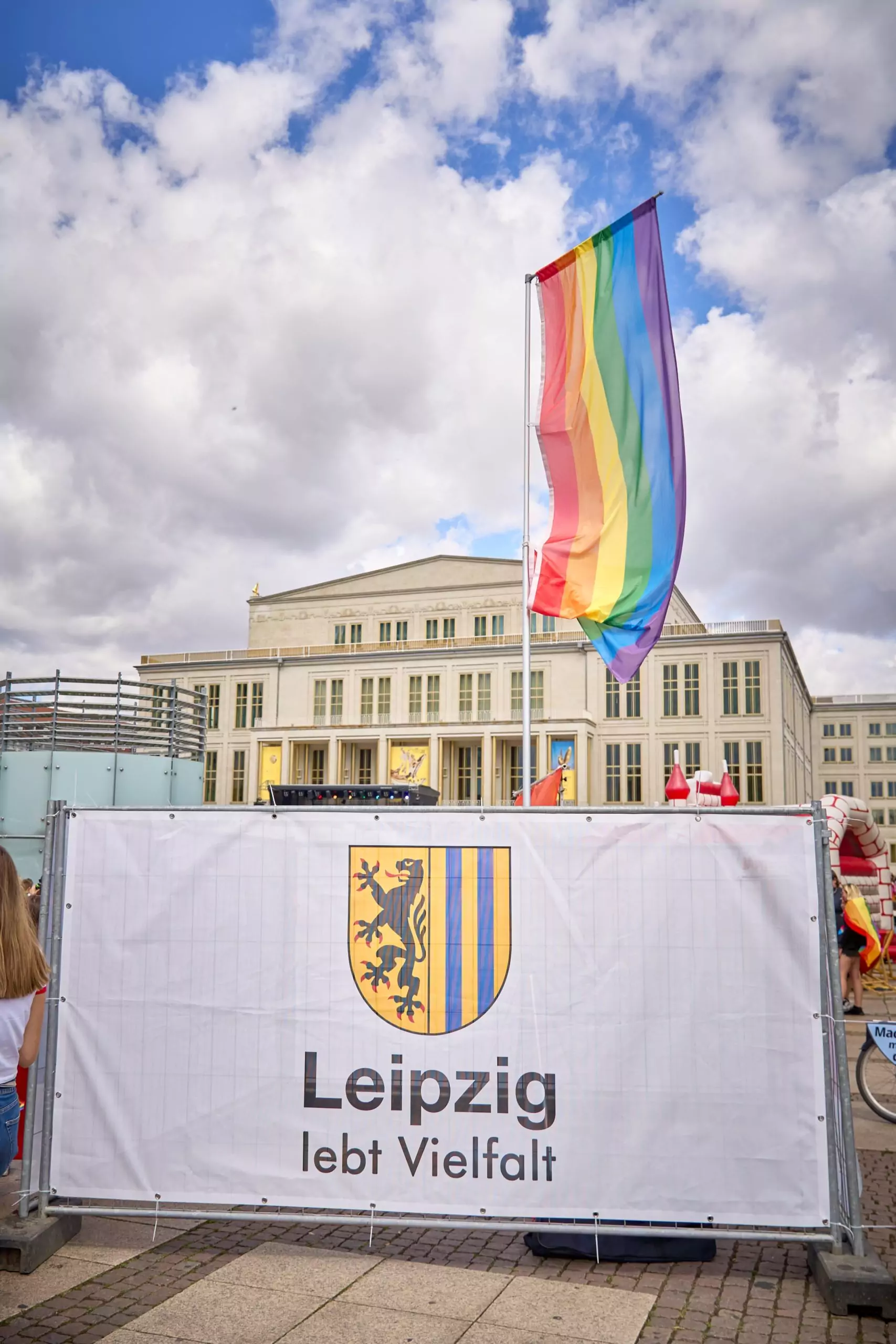 Werbebanner der Stadt Leipzig vor einer gehissten Regenbogenfahne