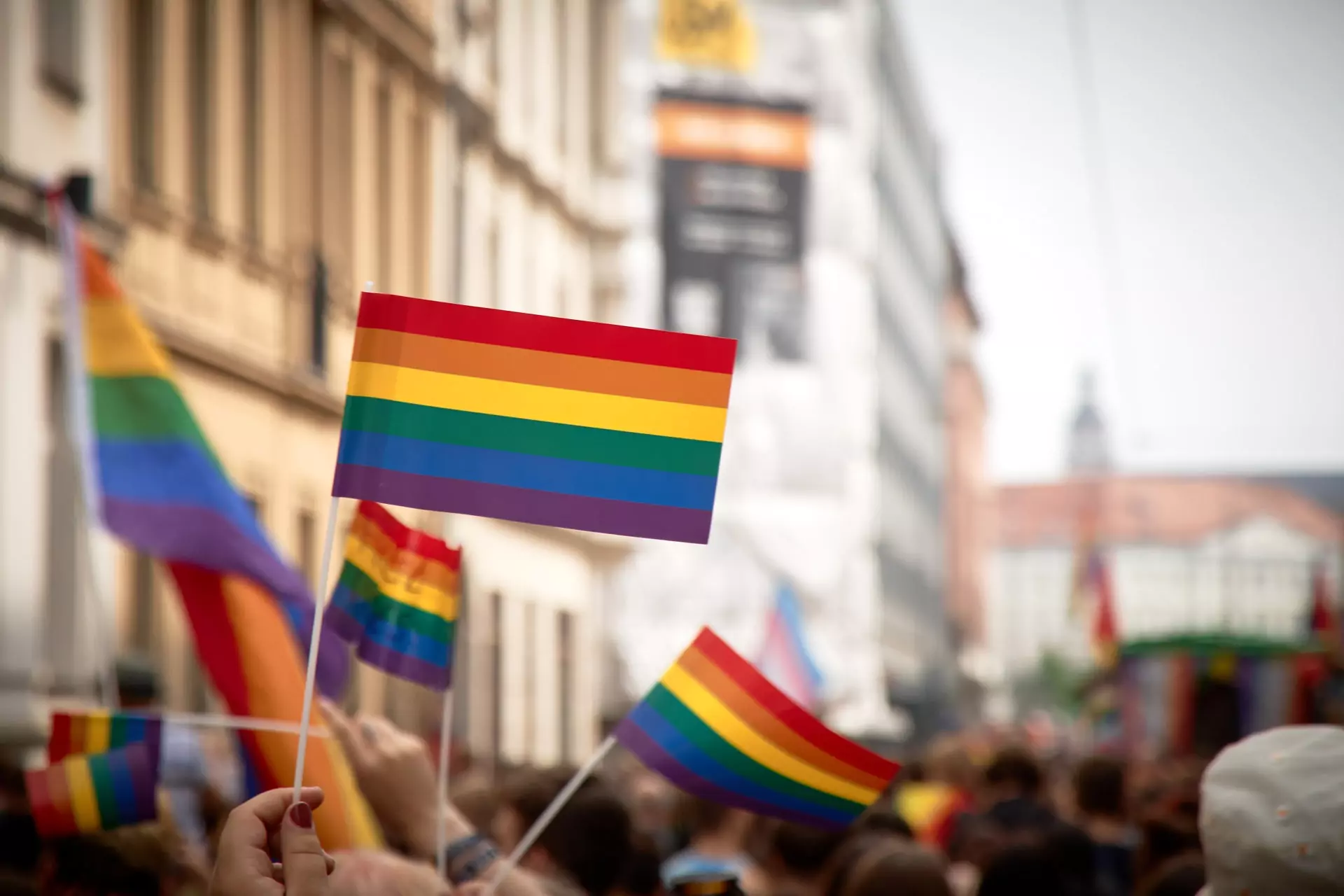 Regenbogenfähnchen werden in die Luft gehalten